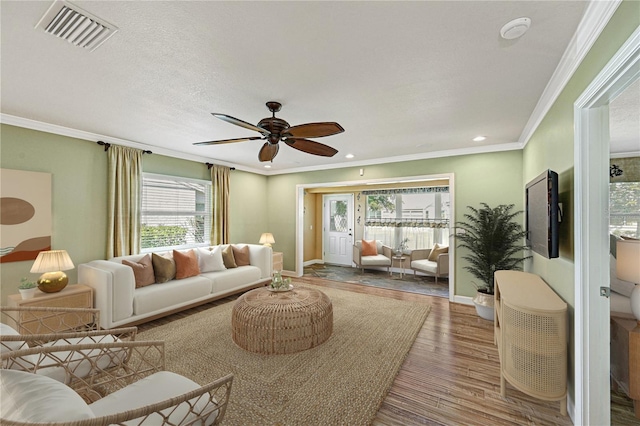 living room featuring hardwood / wood-style floors, a textured ceiling, ornamental molding, and ceiling fan