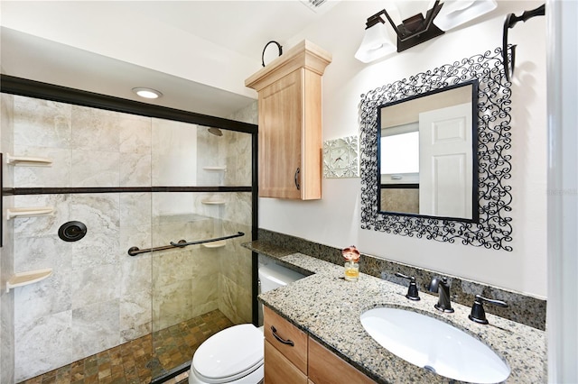 bathroom featuring a tile shower, vanity, and toilet