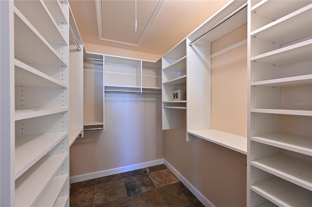 spacious closet featuring attic access and stone finish flooring