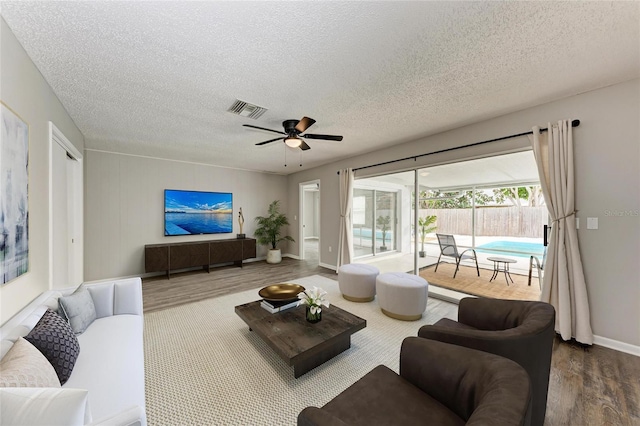 living room with wood-type flooring, ceiling fan, and a textured ceiling