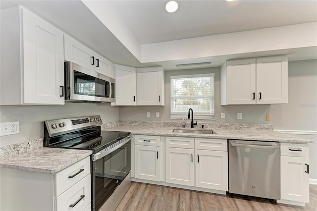 kitchen with white cabinetry, stainless steel appliances, light hardwood / wood-style floors, and sink