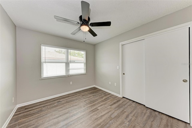 unfurnished bedroom with ceiling fan, a closet, a textured ceiling, and light wood-type flooring