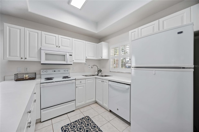 kitchen featuring a raised ceiling, white cabinetry, sink, and white appliances