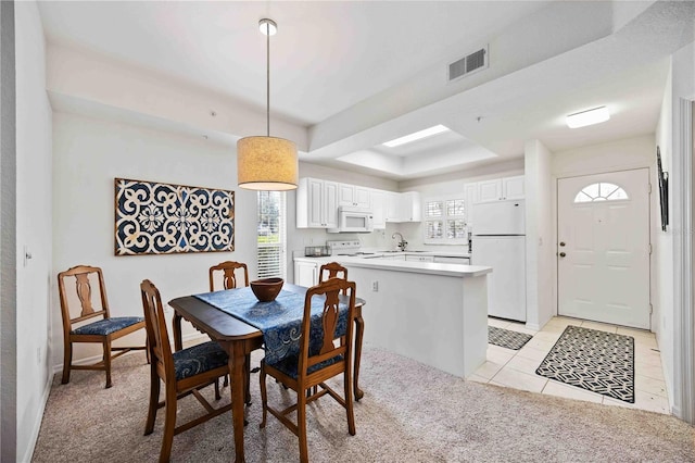 dining room featuring a raised ceiling, sink, a healthy amount of sunlight, and light tile patterned floors