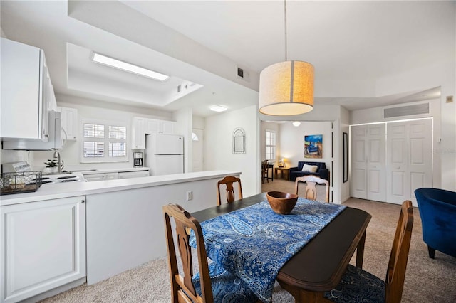 carpeted dining area featuring a raised ceiling