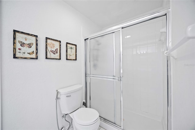 bathroom featuring toilet and a shower with door