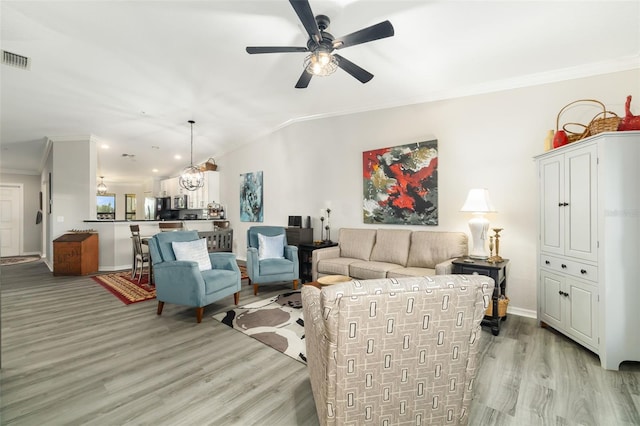 living room with crown molding, lofted ceiling, ceiling fan with notable chandelier, and light hardwood / wood-style flooring