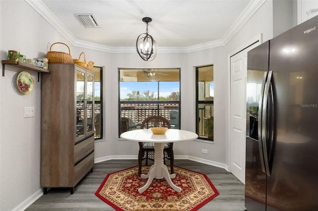 entryway with dark wood-type flooring, ornamental molding, and a notable chandelier