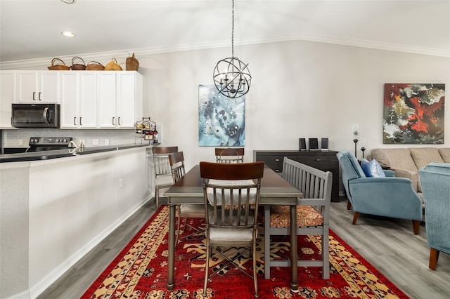 dining space featuring an inviting chandelier, dark wood-type flooring, ornamental molding, and vaulted ceiling