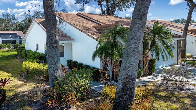 view of side of home with a lanai and a lawn