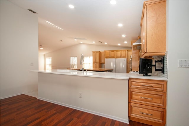 kitchen with white refrigerator, lofted ceiling, kitchen peninsula, and dark wood-type flooring