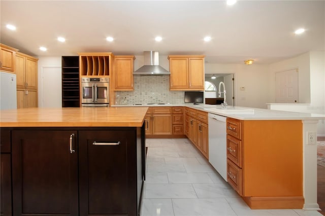 kitchen with white appliances, a center island, butcher block countertops, and wall chimney range hood