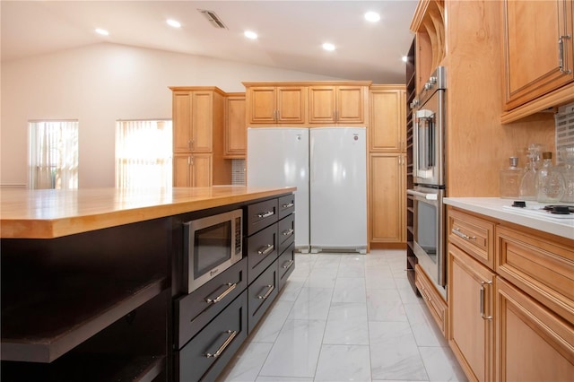 kitchen with stainless steel appliances, lofted ceiling, butcher block counters, and backsplash