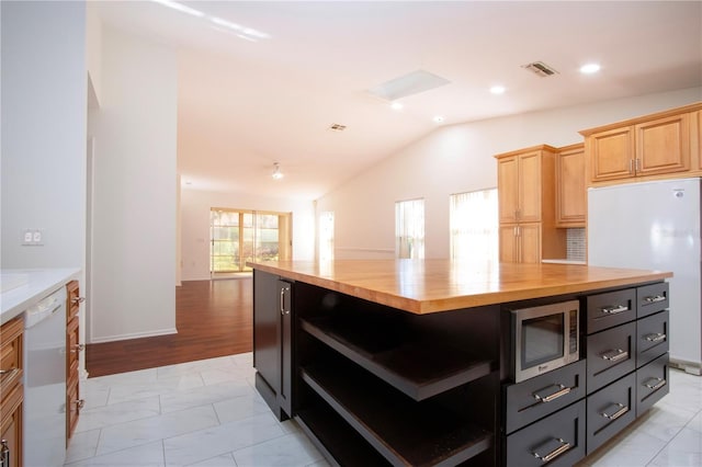 kitchen with lofted ceiling, butcher block countertops, white appliances, and light brown cabinets