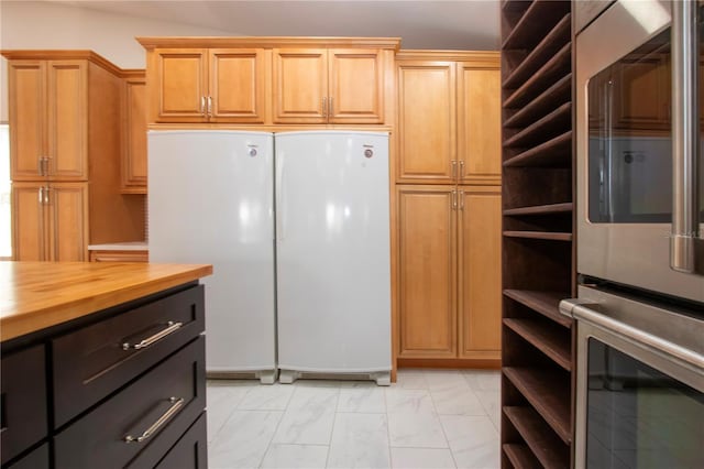 kitchen featuring white refrigerator, butcher block counters, and double oven