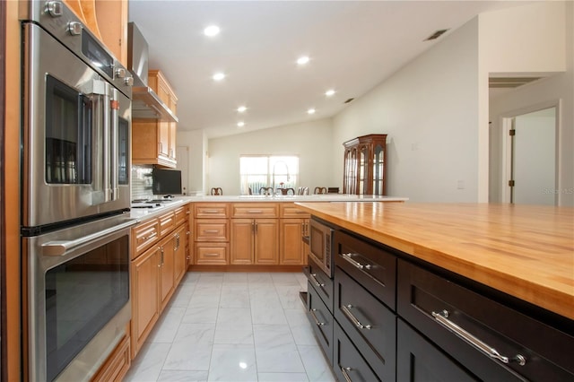 kitchen featuring vaulted ceiling, stainless steel microwave, butcher block countertops, refrigerator, and white gas cooktop