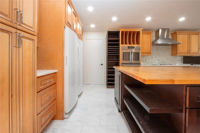 kitchen with white appliances, wood counters, wall chimney exhaust hood, and tasteful backsplash