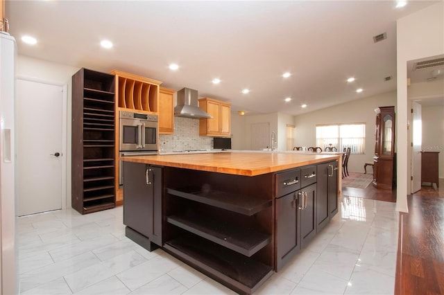 kitchen featuring butcher block countertops, backsplash, stainless steel double oven, a center island, and wall chimney range hood