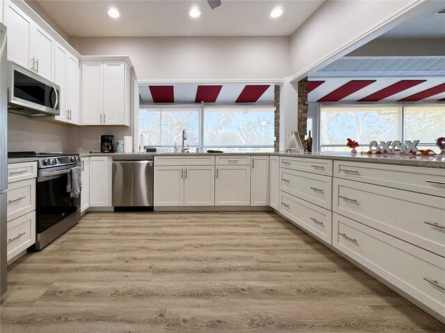 kitchen featuring appliances with stainless steel finishes, white cabinets, and light hardwood / wood-style flooring