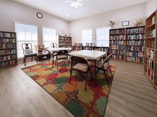 recreation room with ceiling fan, wood-type flooring, and a textured ceiling