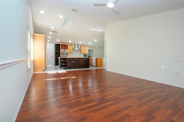 unfurnished living room featuring dark wood-type flooring and ceiling fan