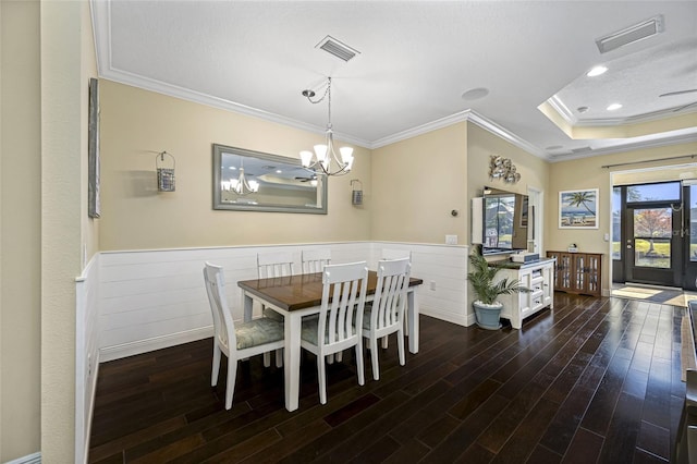 dining space featuring crown molding, dark wood-type flooring, and an inviting chandelier