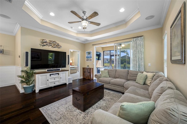 living room featuring dark hardwood / wood-style flooring, a tray ceiling, crown molding, and ceiling fan