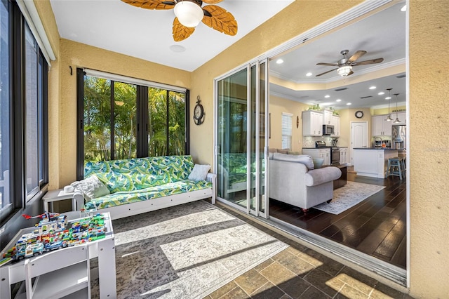 sunroom / solarium with ceiling fan and a raised ceiling