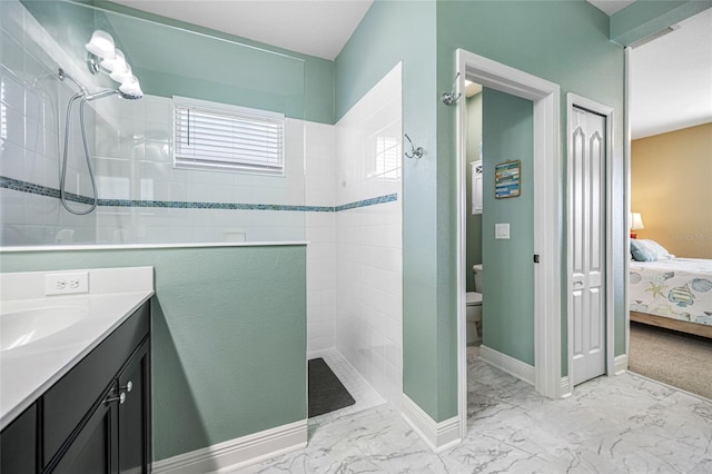 bathroom with vanity, tiled shower, and toilet