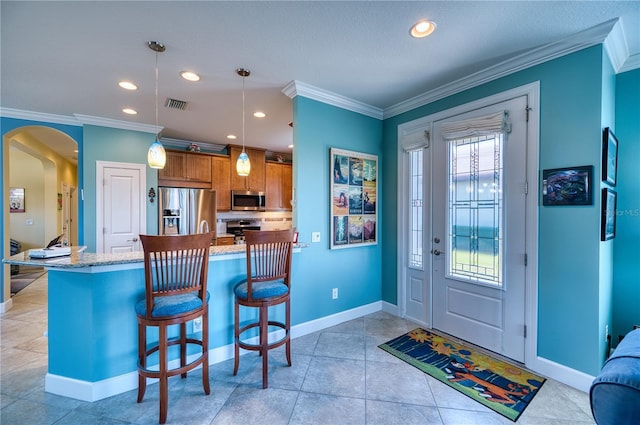 kitchen featuring decorative light fixtures, ornamental molding, appliances with stainless steel finishes, a kitchen breakfast bar, and kitchen peninsula