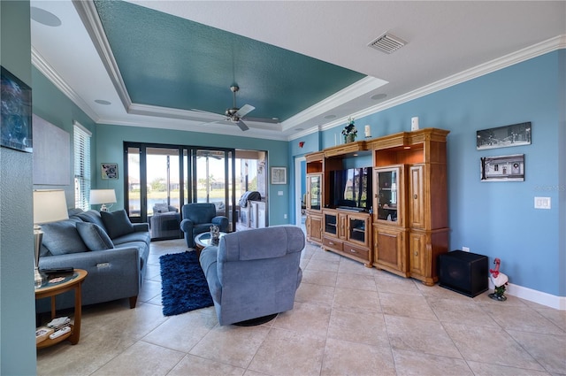 living room featuring ornamental molding, a raised ceiling, ceiling fan, and light tile patterned flooring