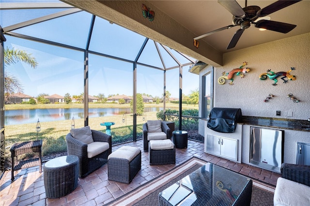 view of patio / terrace with exterior kitchen, an outdoor hangout area, grilling area, glass enclosure, and a water view