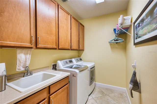 washroom featuring washer and dryer, sink, cabinets, light tile patterned floors, and a textured ceiling