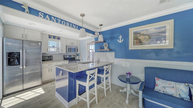 kitchen featuring hanging light fixtures, a kitchen bar, white cabinets, and appliances with stainless steel finishes