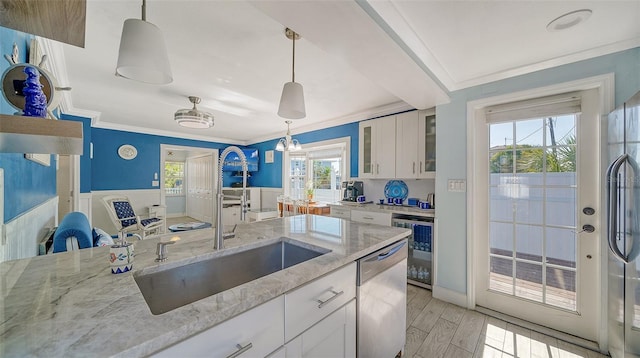 kitchen with sink, appliances with stainless steel finishes, pendant lighting, light stone countertops, and white cabinets