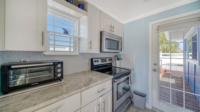 kitchen featuring light stone countertops, white cabinetry, appliances with stainless steel finishes, and tasteful backsplash