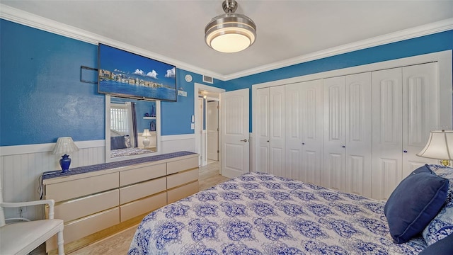 bedroom featuring light hardwood / wood-style flooring, ornamental molding, and a closet