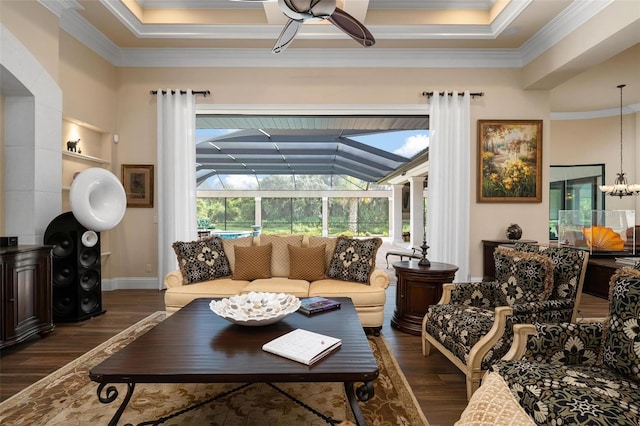 living room with ornamental molding, dark wood-type flooring, ceiling fan, and a tray ceiling