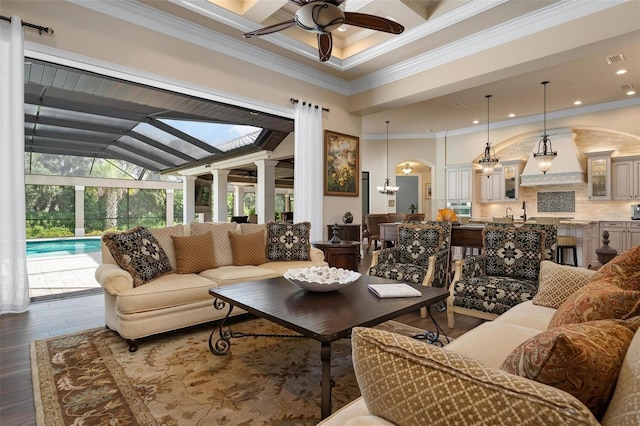 living room with a towering ceiling, ceiling fan with notable chandelier, coffered ceiling, crown molding, and dark wood-type flooring