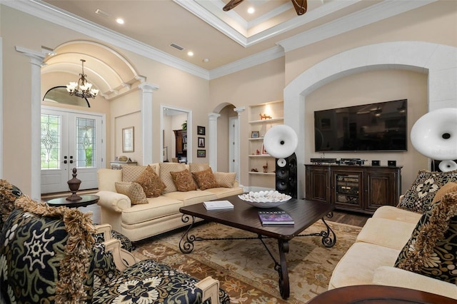 living room with crown molding, built in features, hardwood / wood-style floors, decorative columns, and french doors