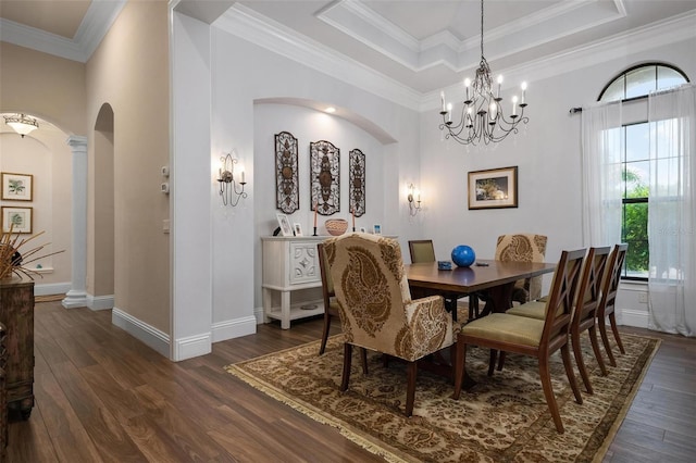 dining area with dark hardwood / wood-style flooring, crown molding, decorative columns, and a raised ceiling