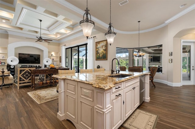 kitchen featuring decorative light fixtures, an island with sink, sink, dark hardwood / wood-style flooring, and light stone countertops