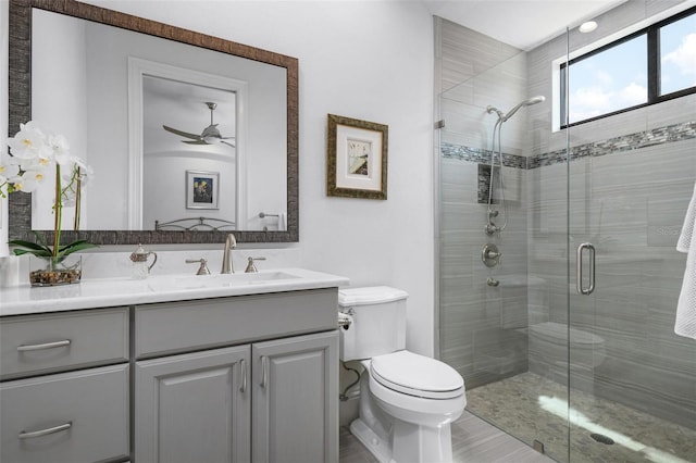 bathroom with ceiling fan, vanity, toilet, and a shower with door