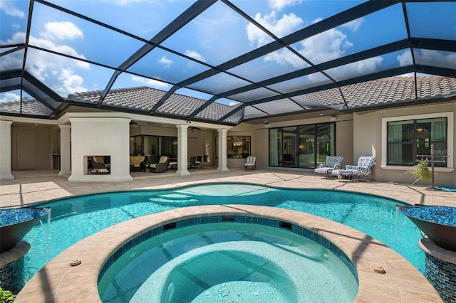 view of swimming pool with an outdoor fireplace, an in ground hot tub, ceiling fan, glass enclosure, and a patio area