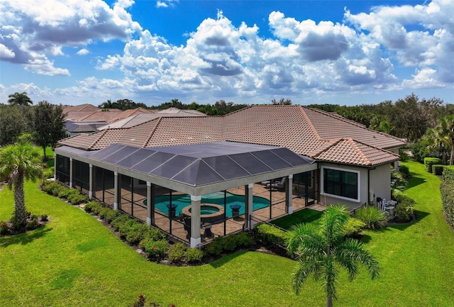 back of house with a swimming pool with hot tub, a lanai, a patio area, and a lawn