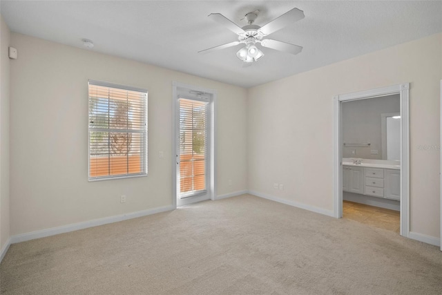 unfurnished bedroom with ceiling fan, light colored carpet, access to exterior, and ensuite bath