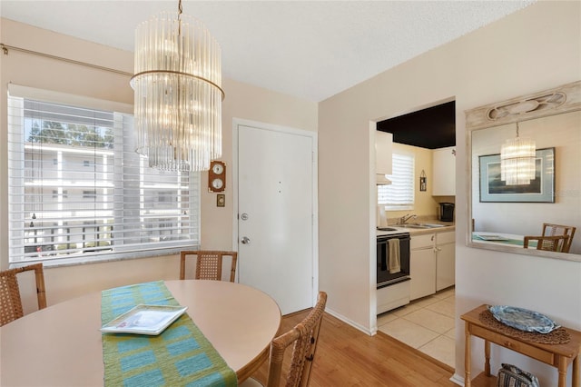 dining room featuring an inviting chandelier, sink, and light wood-type flooring