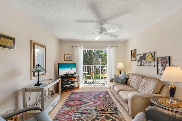 living room with a textured ceiling, light hardwood / wood-style flooring, and ceiling fan