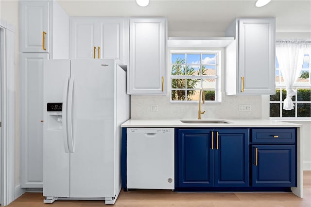 kitchen with blue cabinets, tasteful backsplash, sink, and white appliances