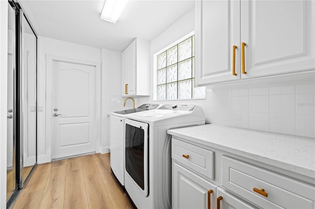 laundry room featuring separate washer and dryer, light hardwood / wood-style floors, and cabinets